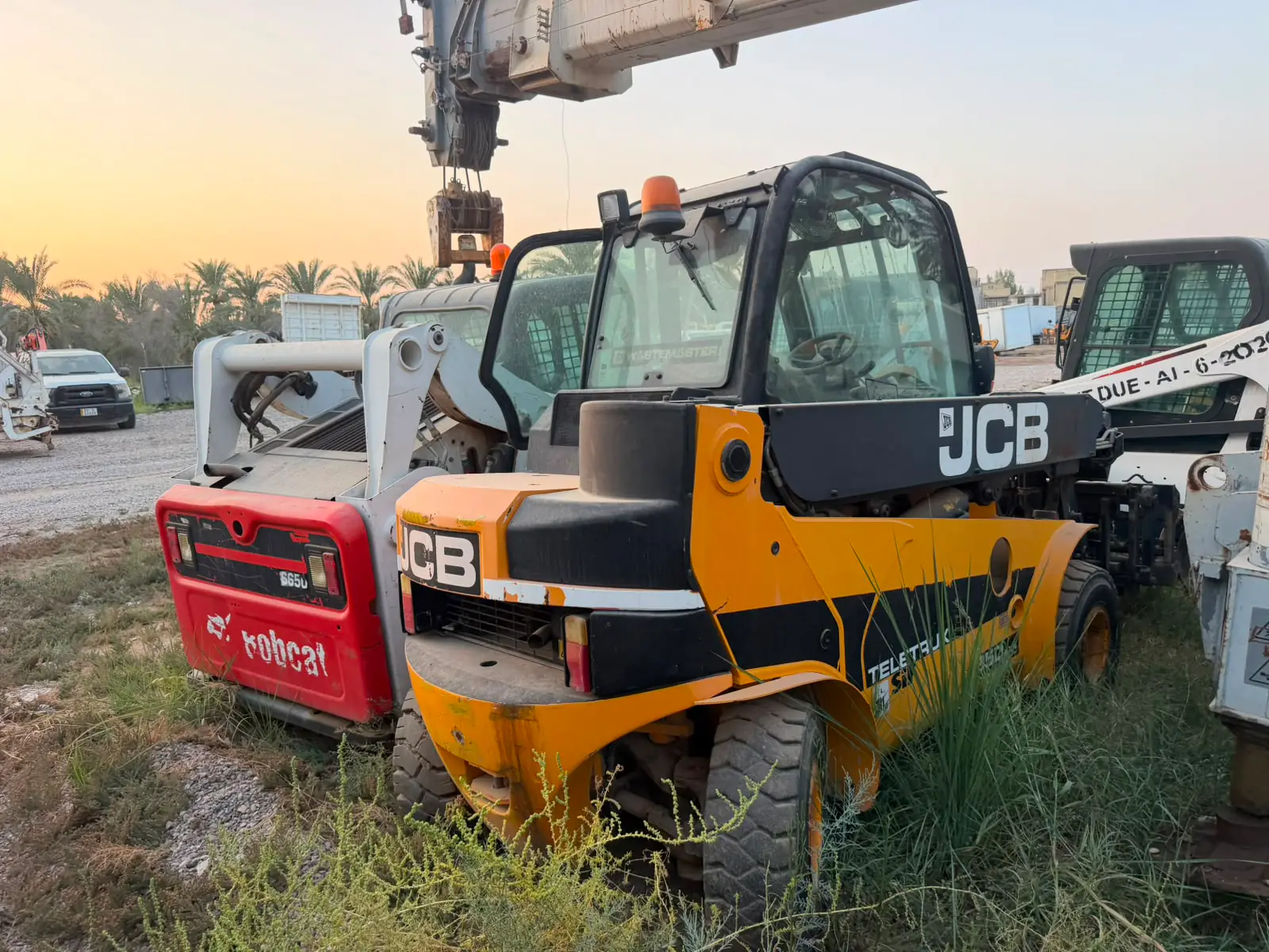 Crane hook and telehandler on site at dusk